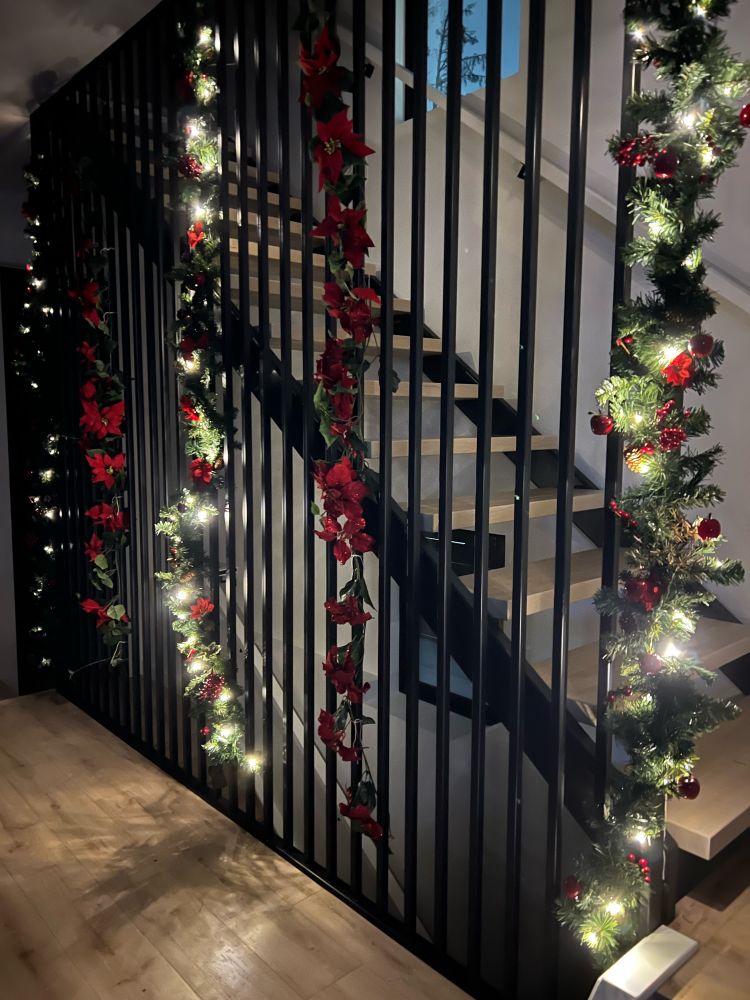 Garland with Christmas lights and poinsettia on a staircase 