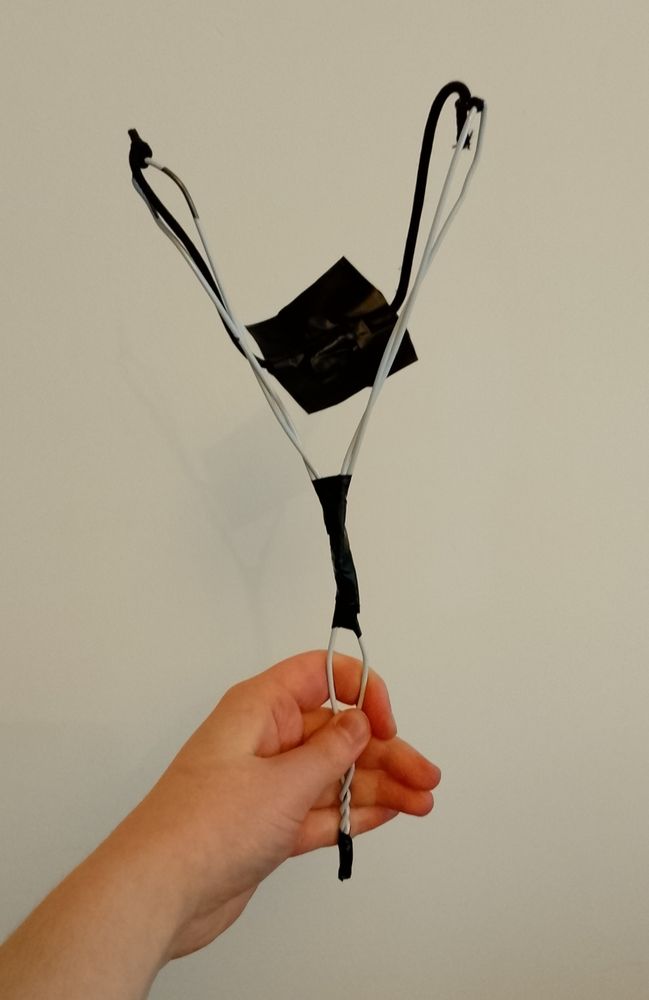 Photo of a DIY slingshot made from a wire coat hangar, an elastic hairband, and tape