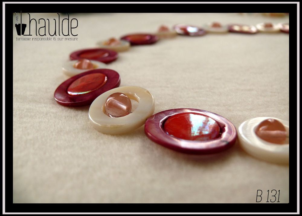 Collier composé de cercles de nacre blanc avec une perle de cristal rose en leur centre alternés avec des cercles de nacre rouges avec un palet de nacre rose irisé en leur centre Vue en gros plan du collier