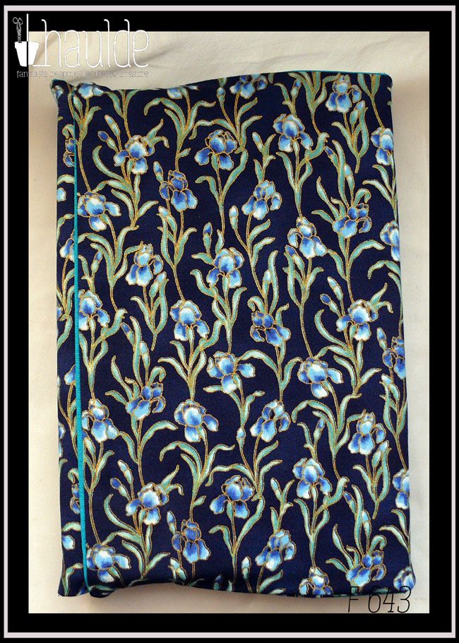 Protège livre en tissu bleu marine imprimé iris bleus; Les iris sont sur tige avec leurs feuilles et détouré d'une très fine ligne dorée Vu fermé