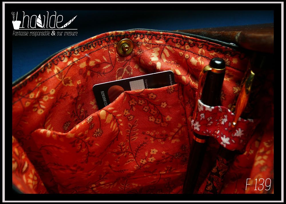 Vue de la poche intérieure et des boucles pour stylo, tissu orange imprimé motifs végétaux fleuris très fins marron et jaune