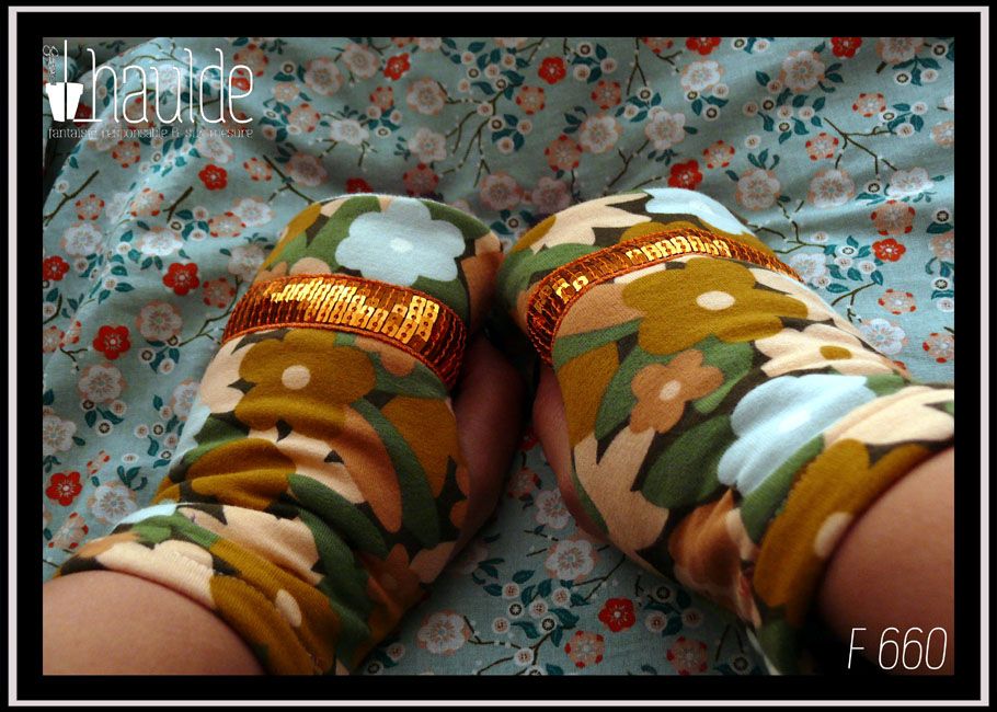 Mitaines en jersey gratté imprimé, fleurs ocre, corail, écru et bleu pâle sur fond noir avec feuilles vertes stylisées Un galon de sequins carrés oranges sur 5 rangs décore le dessus des phalanges Vue de la paire de dessus, portée