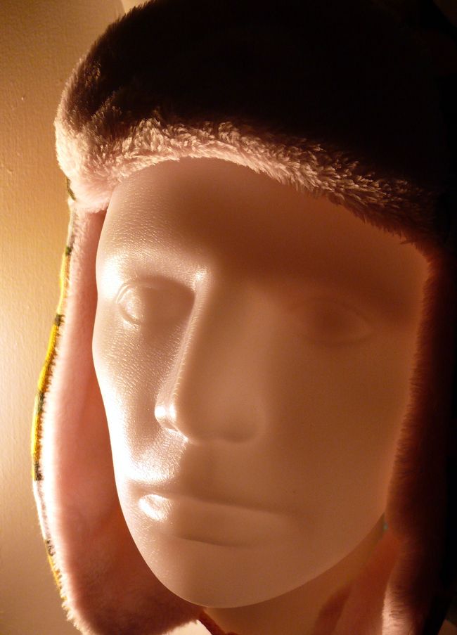 tête de mannequin en plastique portant une chapka dans les tons roses (éclairage artificiel qui brouille les couleurs)