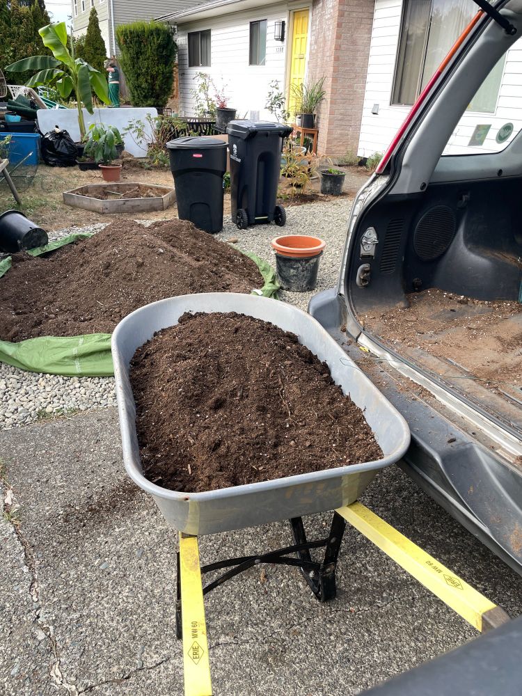 Image of a wheelbarrow full of dirt and a large pile of soil
