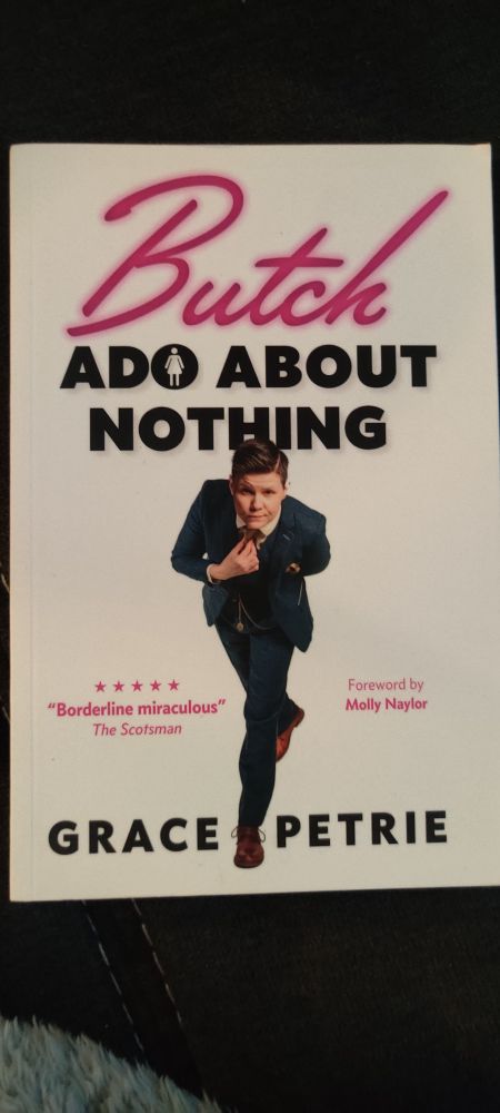 Buchcover von Butch Ado About Nothing von Grace Petrie. „Butch“ in pinker Schreibschrift, „ADO ABOUT NOTHING“ in schwarzer Blockschrift. Im O von „ADO“ ist ein stilisiertes Symbol einer Person mit Rock dargestellt. Grace Petrie ist im Anzug abgebildet.