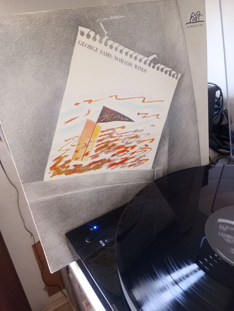 Picture of the LP cover of 'Nomadic Winds' by George Sams standing adjacent to the LP playing on a turntable 