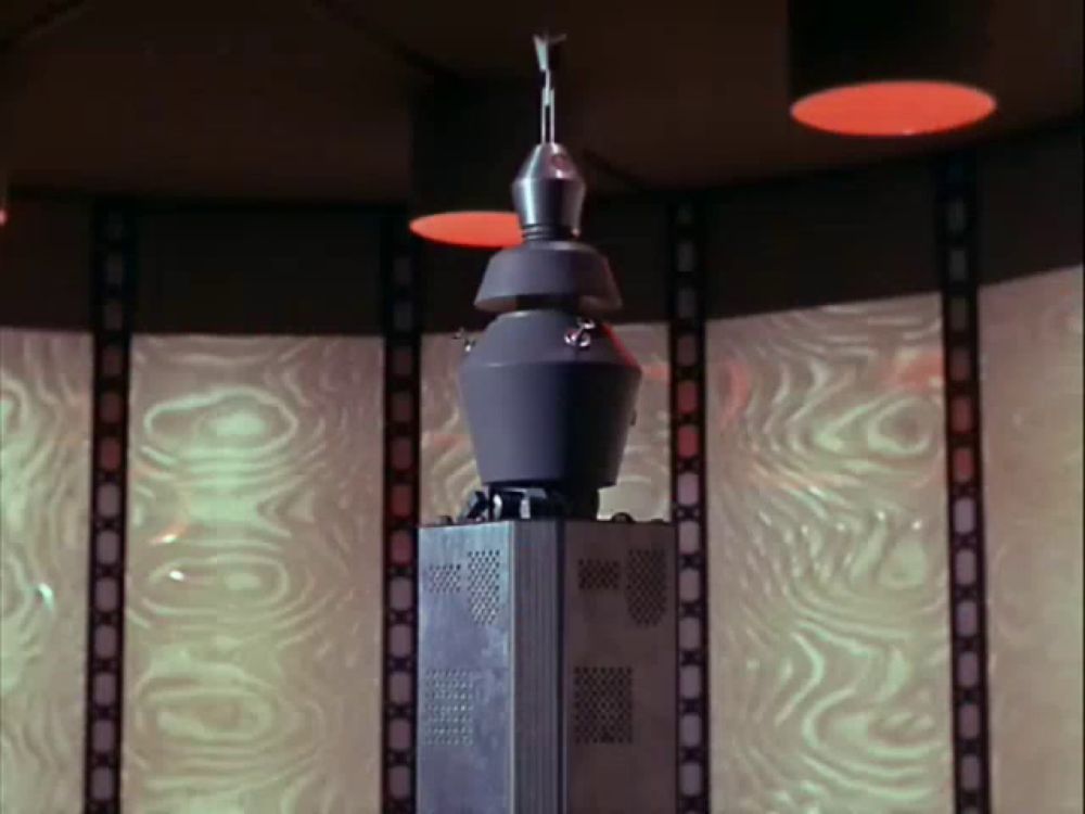 a gray tower with a red light on top of it in a room