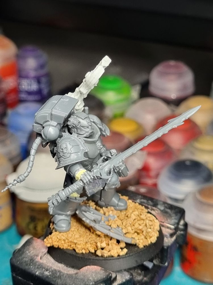 A Techmarine stands holding a daemon weapon, contemplating it. Could it be used for the good of the Imperium? (Top view) 
