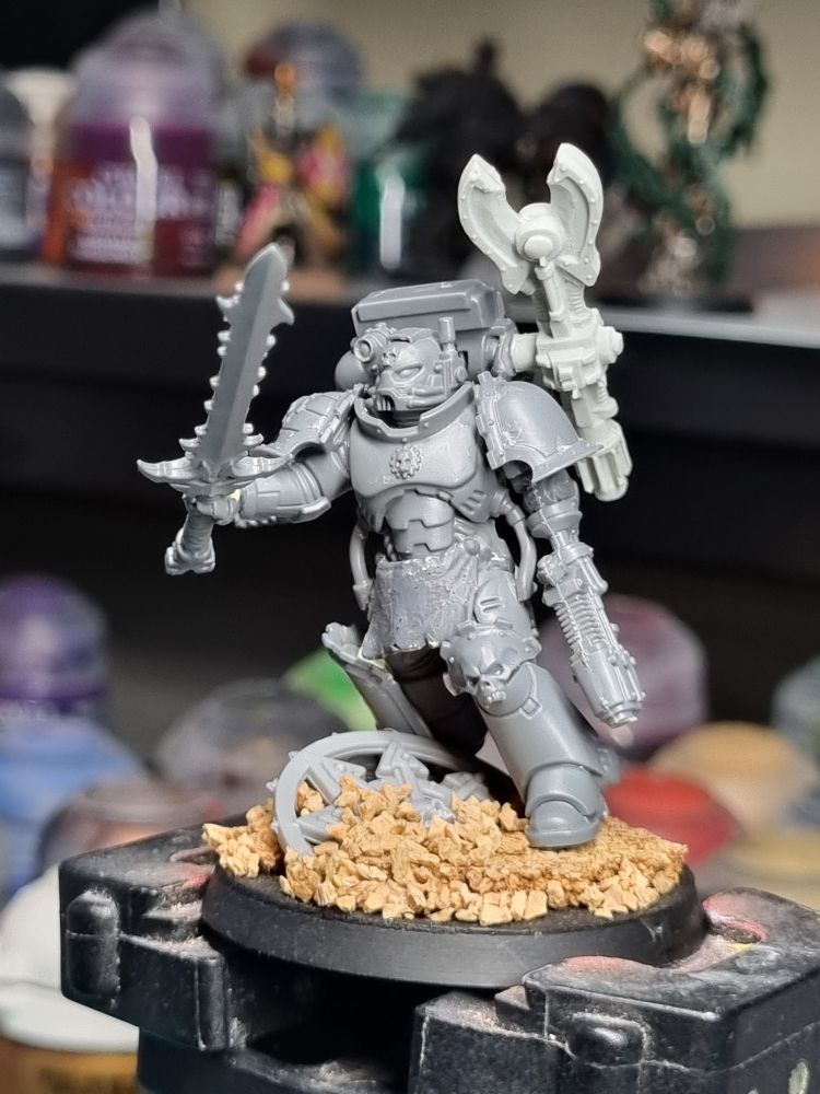A Techmarine stands holding a daemon weapon, contemplating it. Could it be used for the good of the Imperium? (Front view) 