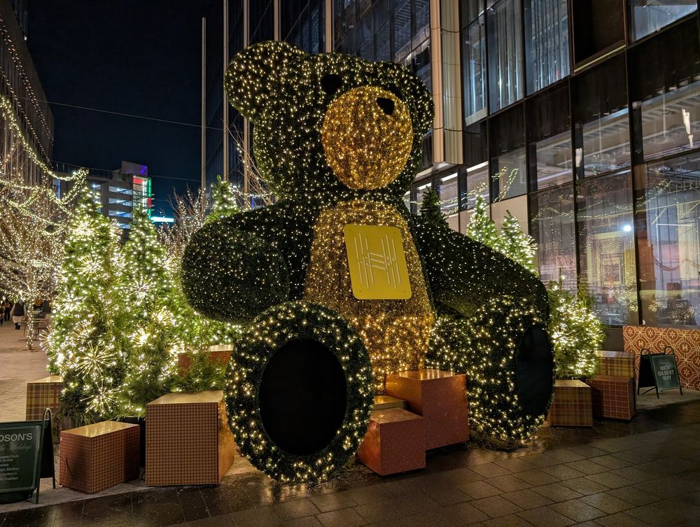 A large, lit-up teddy bear in front of the new Hudson's Building in Detroit Michigan.