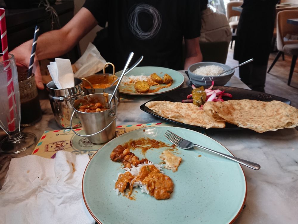 Restaurant table with plates of Indian food and breads