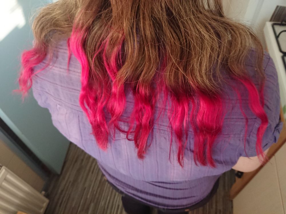 Woman seen from the back with shoulder length brown hair. The last 10 cm or so of hair is dyed bright pink