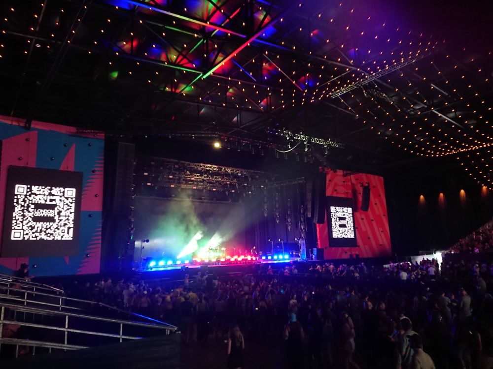 Empty stage in a big, daek festival fent. Some coloured lights are shining on stage.