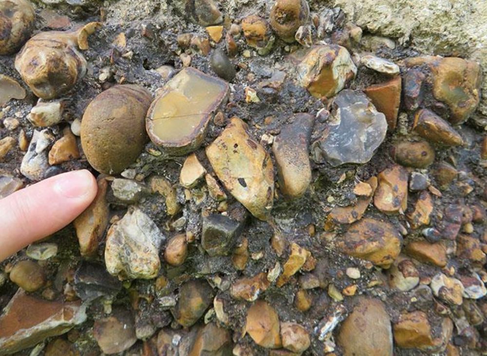 Detail of the geological appearance of ferricrete with my finger for scale. The stone is composed of a rough breccia of flint stained a rusty red colour. The Ferricrete in this case is an iron-cemented flint breccia of Pleistocene to Holocene age. Read full details in the document in the link in the post. 