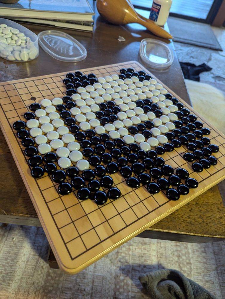 A black and white pixel art panda drawn with go pieces 