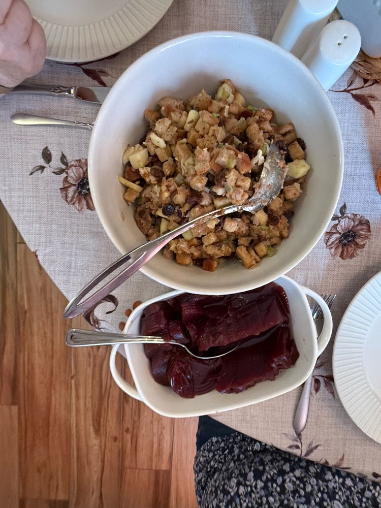 Overhead photo of two Thanksgiving sides on a table. The dishes contain dressing and cranberries. 