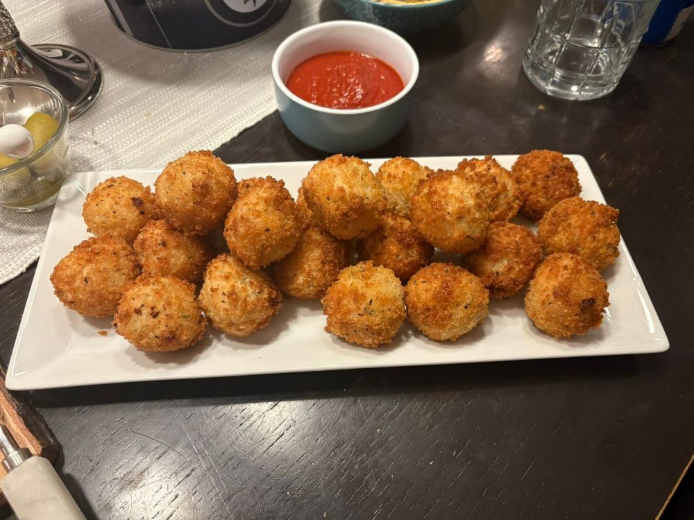 A plate of homemade arincini. Arborio rice balls stuffed with Boursin cheese, breaded and deep fried, served with homemade marinara. 