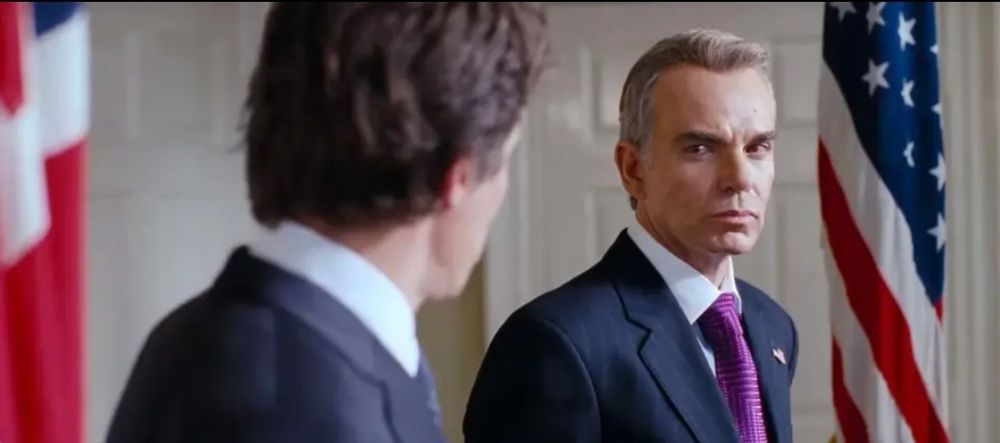 Pic from movie Love Actually. Hugh Grant as PM looks at a stern Billy Bob Thornton as US president.