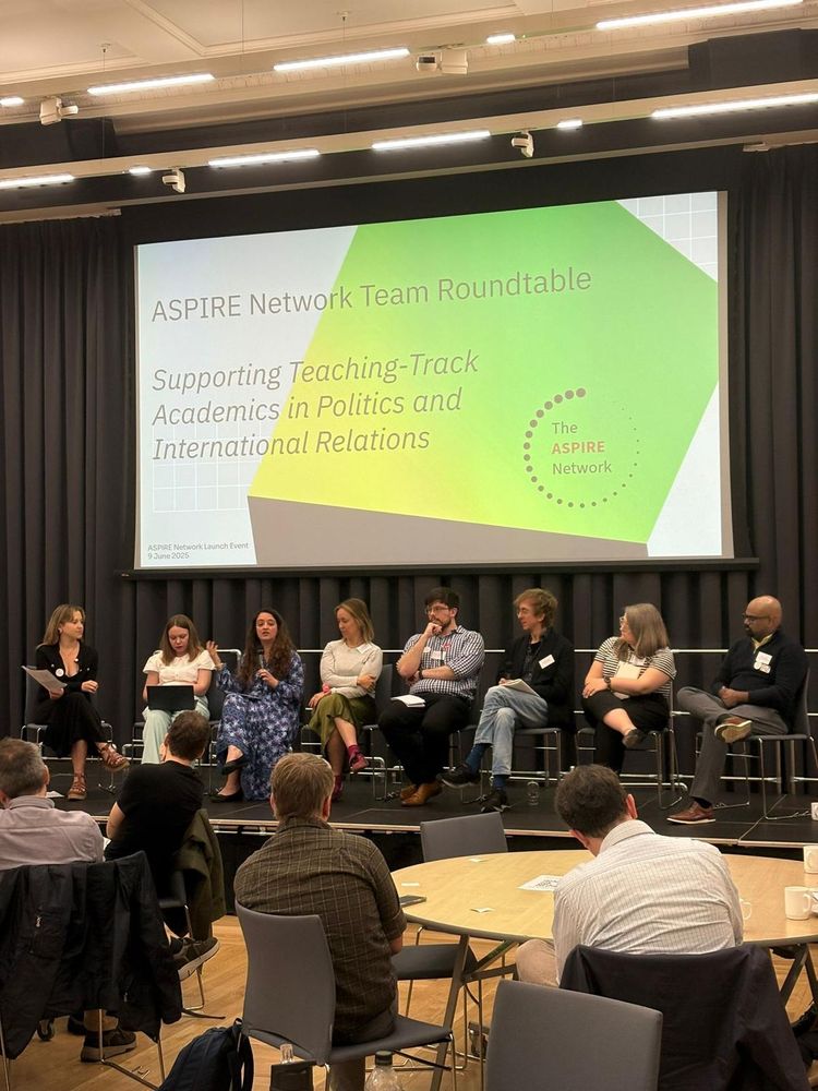 Image of 8 people on a stage in front of a slide saying "supporting teaching track academics in politics and international relations" 