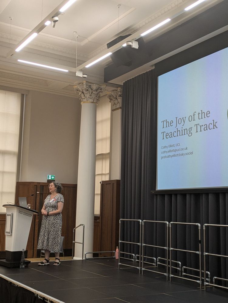 Image of Professor Cathy Elliot on stage with a PowerPoint of her presentation joy of the teaching track behind her.
