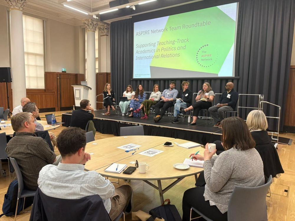 Image of 8 people on a stage in front of a slide saying "supporting teaching track academics in politics and international relations" 