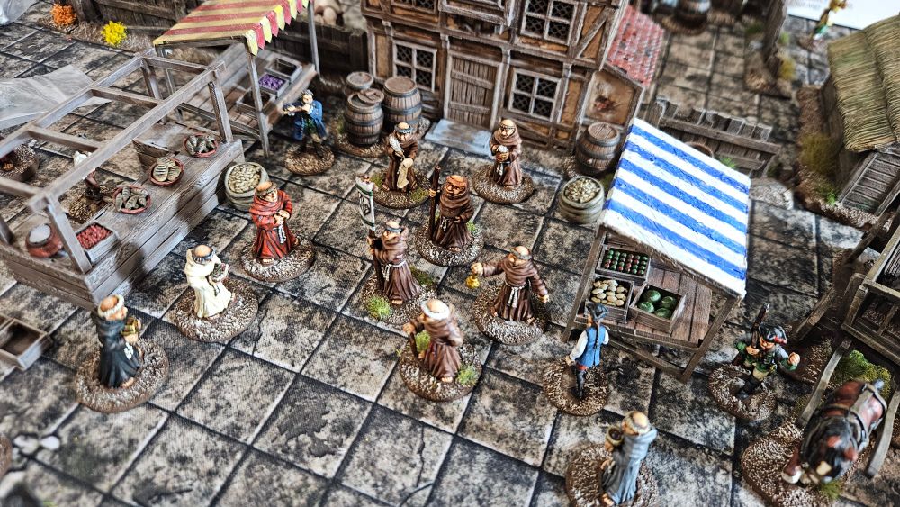 28mm monks in a marketplace with a building to their rear. 