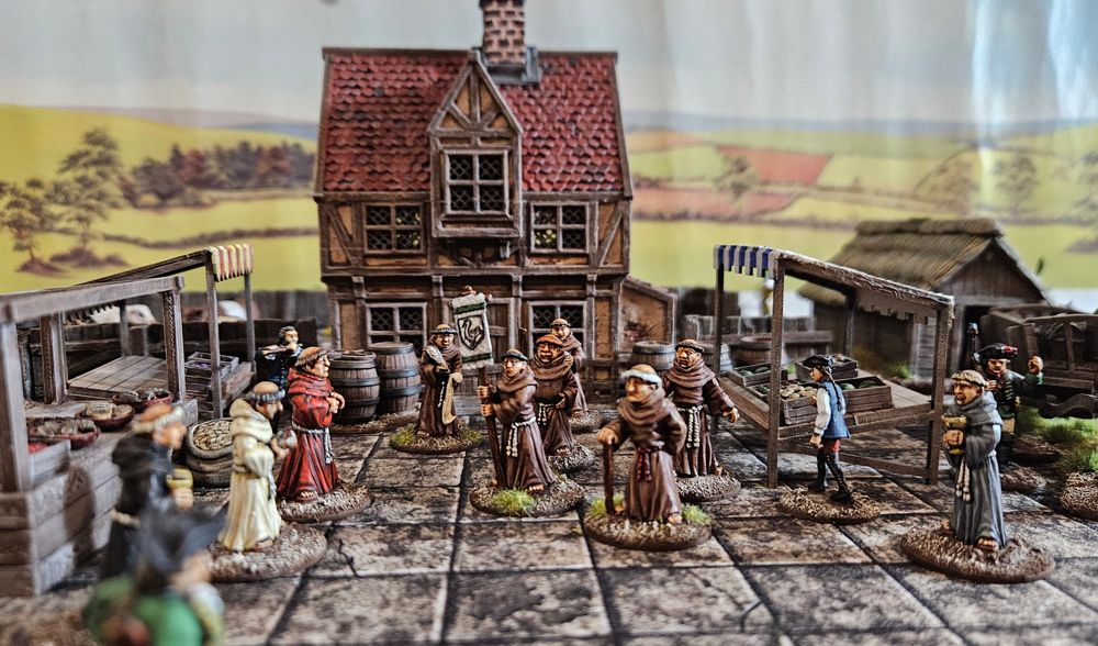 28mm monks in a marketplace with a building to their rear. 