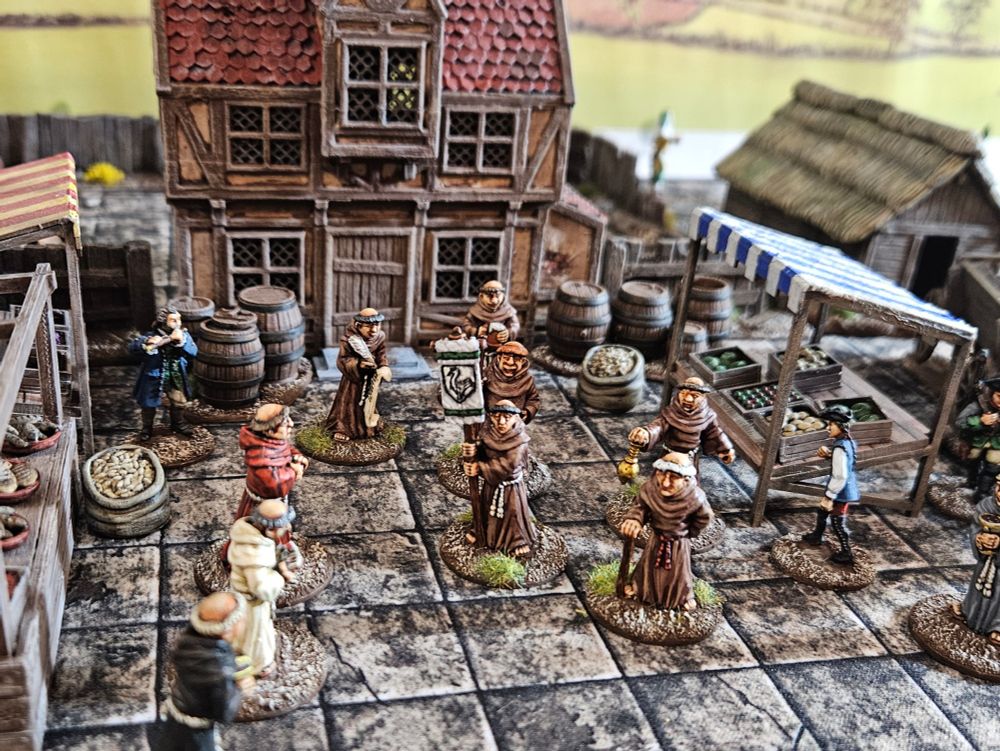 28mm monks in a marketplace with a building to their rear. 