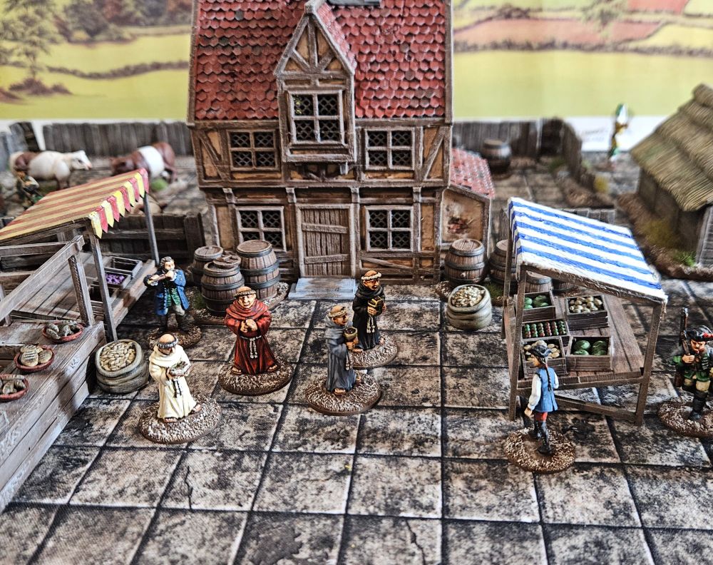 28mm monks in a marketplace with a building to their rear. 