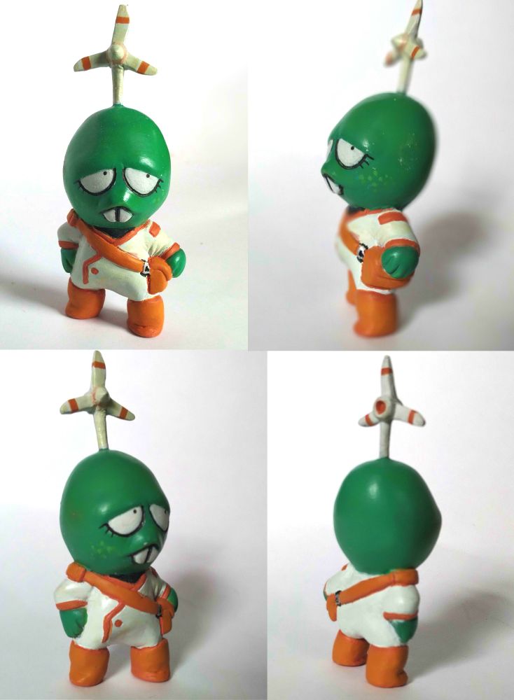 Turbine, a green character with large white eyes with small pupils and eyelashes, freckles, a protruding upper lip with buck teeth, and a wind turbine on her head. She is wearing a white suit with orange accents and a satchel.