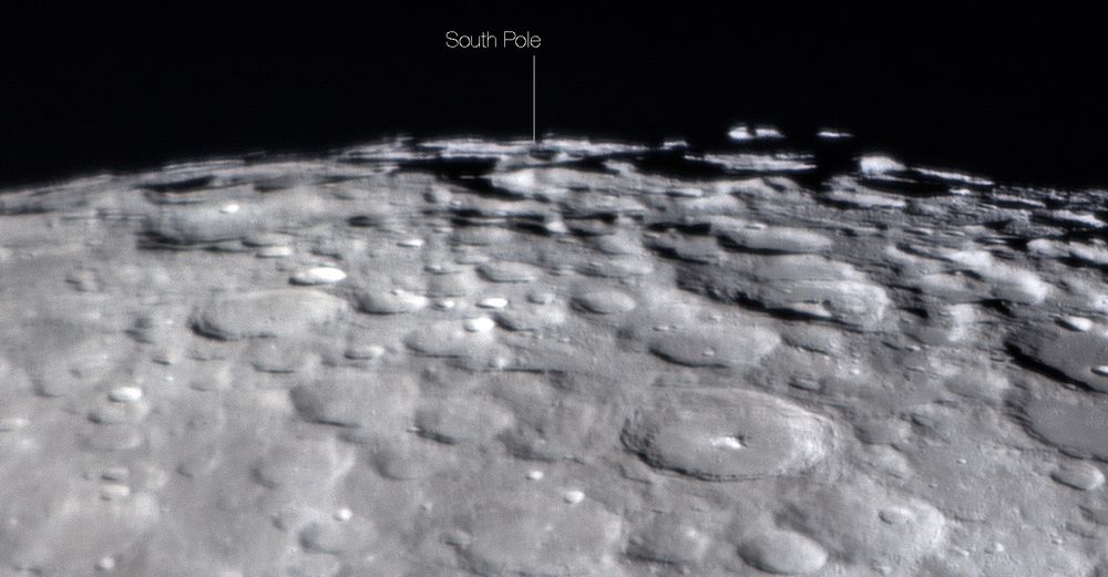 Heavily cratered lunar landscape in shades of grey with black sky above. 