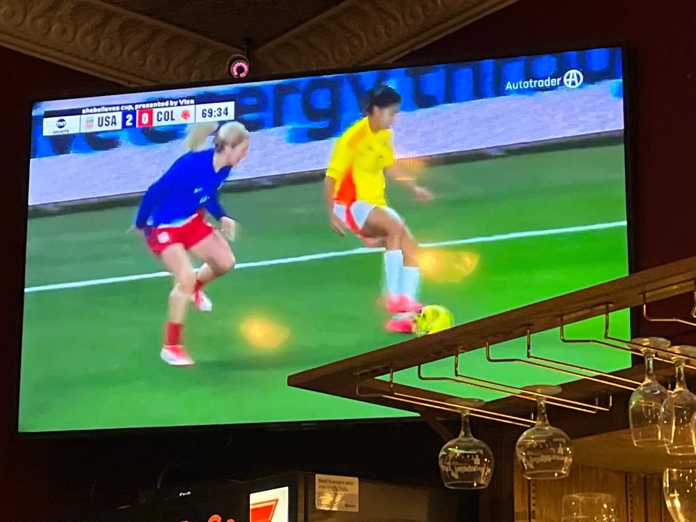 A television in a bar showing the US v Columbia shebelieves cup game