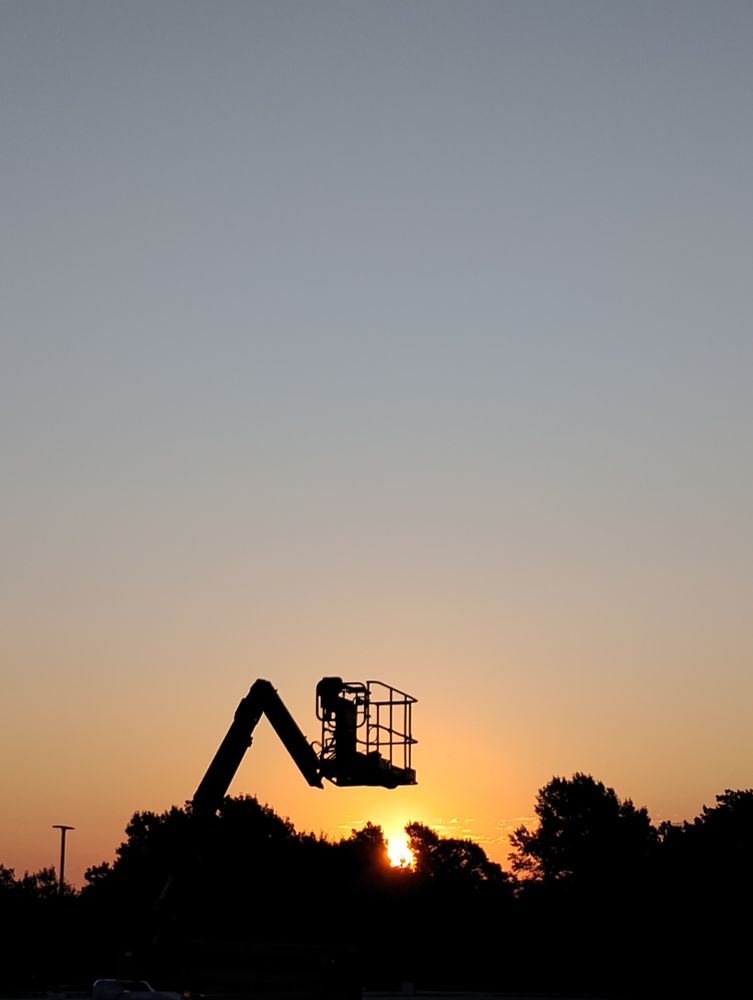 Sunrise behind trees, a light pole and a lift.