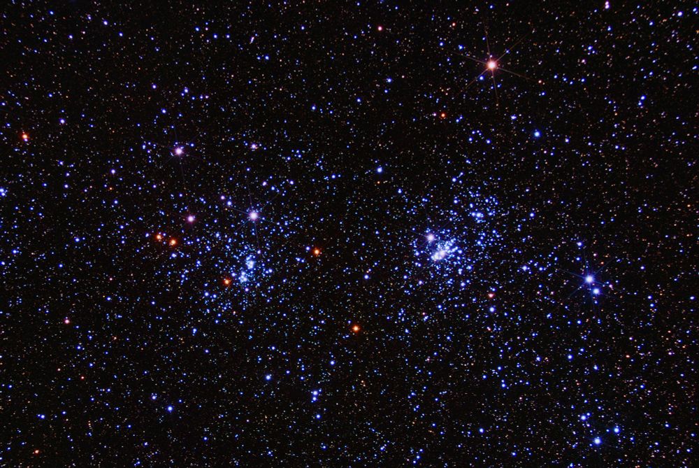 two colorful star clusters with thin diffraction spikes seen on the brighter stars