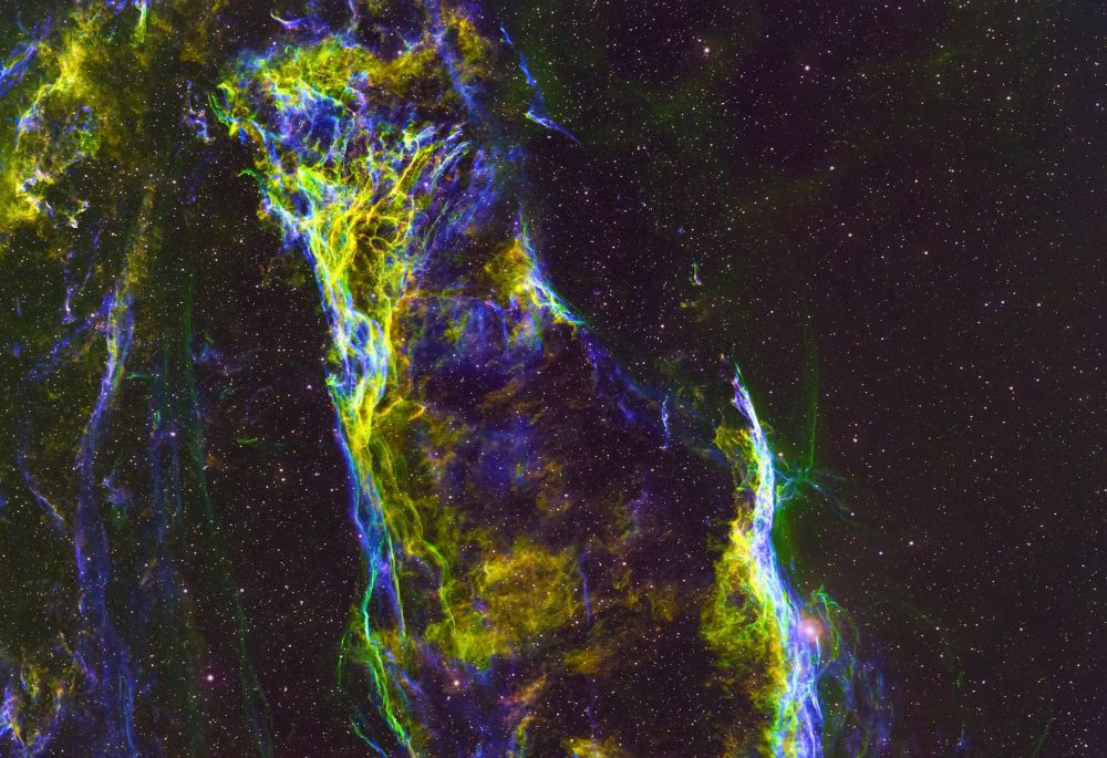 a wispy filamentary cloud of debris left over from a supernova explosion. green is light from hydrogen, blue oxygen, and red sulfur. They mix to give of yellow, cyan, and a little magenta. The best 78 out of 89 240s exposures taken through SHO filters with a Takahashi TSA 120 with 0.7x reducer and ZWO ASI2600MM camera