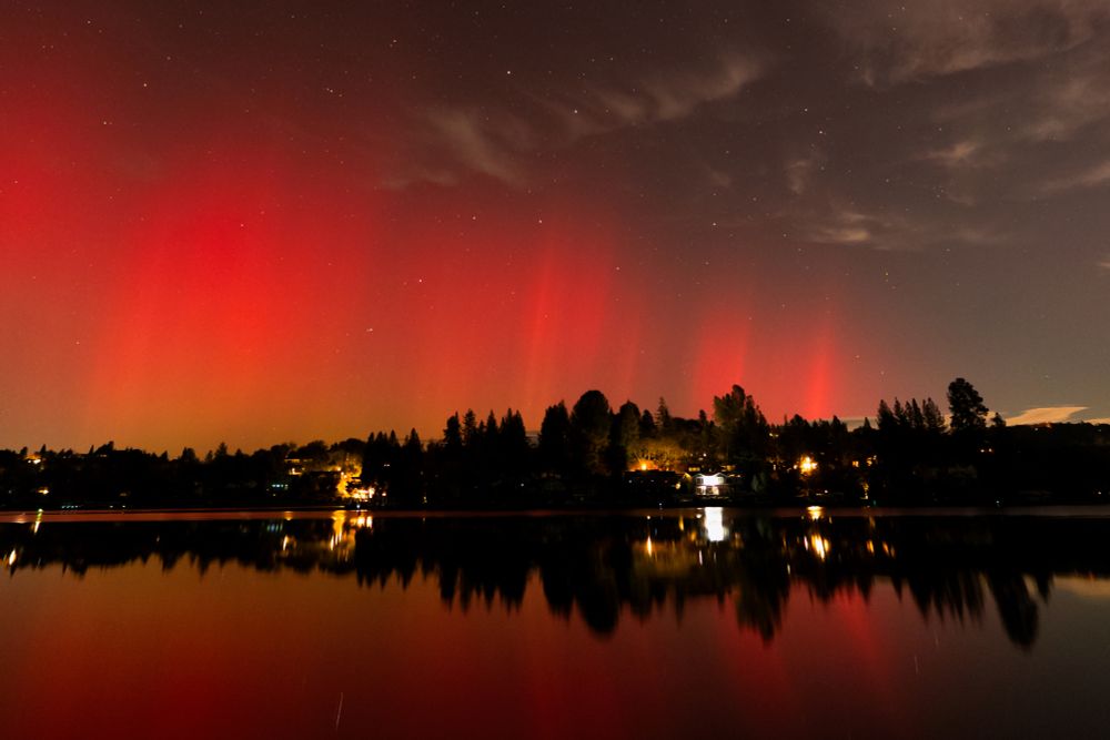 a bright red aurora is reflected in a lake