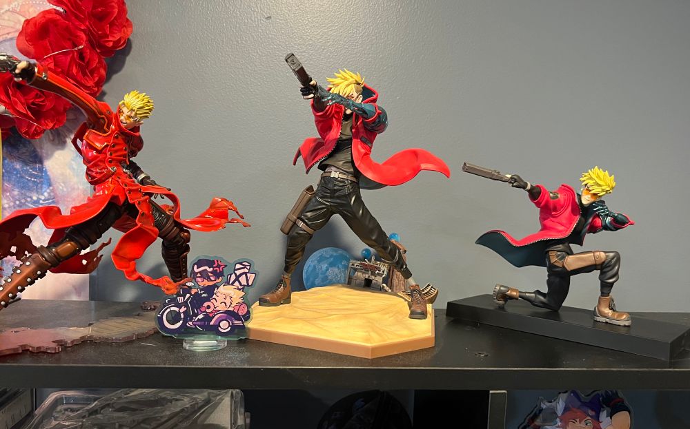 Vash the stampede figurines on a shelf. 3 figurines and one plastic standee