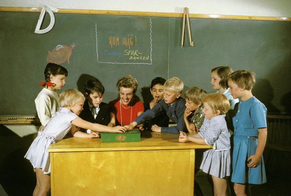 An image depicting a group of kids and a teacher in a classroom