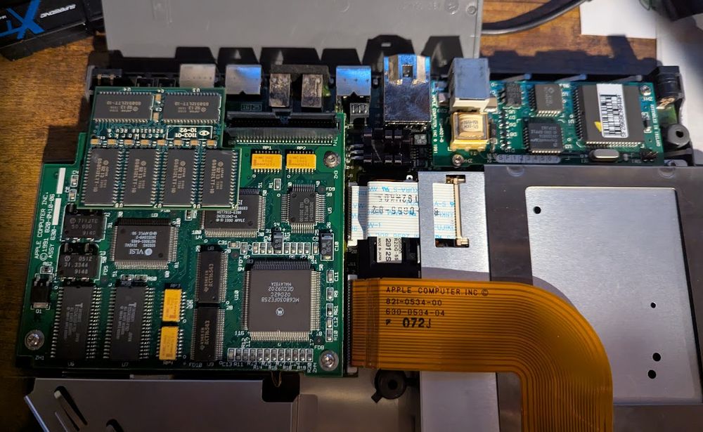 The insides of the powerbook 170 - a RAM upgrade (I think it has 8mb now), the 68030 CPU (with the FPU on the bottom of the CPU/RAM card, out of sight), the connectors/modem exposed, a nice brown ribbon cable to the hard disk, and it's so clean. No leaky caps, no battery corrosion. Just happy and thriving.
