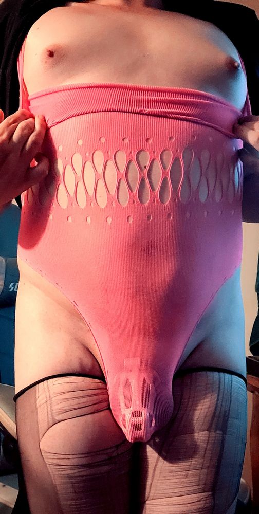 Another erotic selfie this time, I am pulling down the body suit to expose my small titties and nipples. I am still wearing the ripped stockings and pink chastity cage. The image is also editing to give a more vibrant feel.