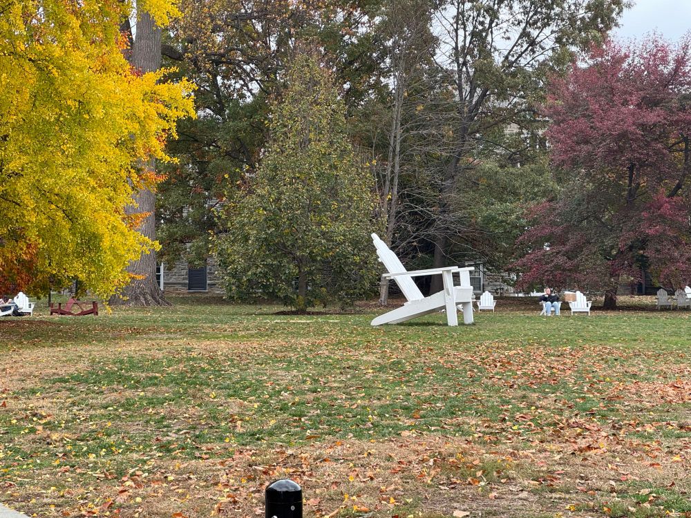 Giant white lounging chair in a grassy area with trees
