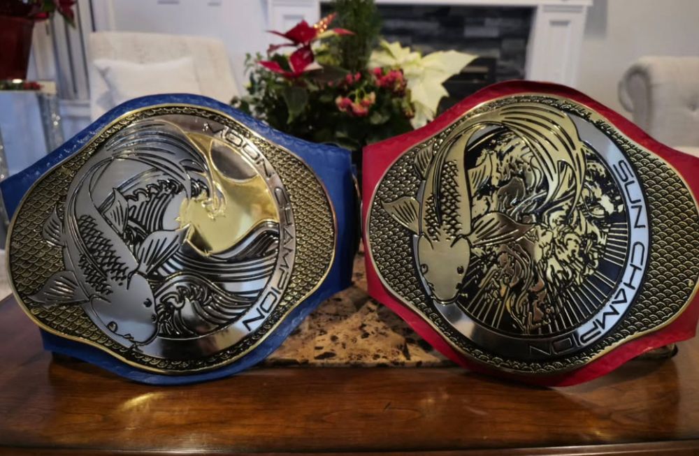 Dusk Pro Wrestling's Sun & Moon tag team title belts with a koi fish design. The Sun belt has a red strap and the Moon belt has a blue strap.