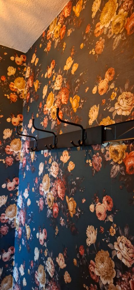 Muur met bloembehang en een lege kapstok