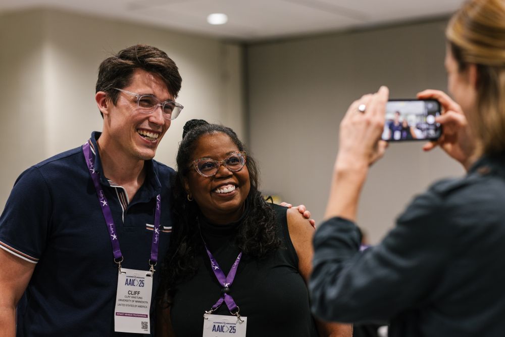 Two AAIC25 attendees pose for a picture taken by a person with their cell phone.
