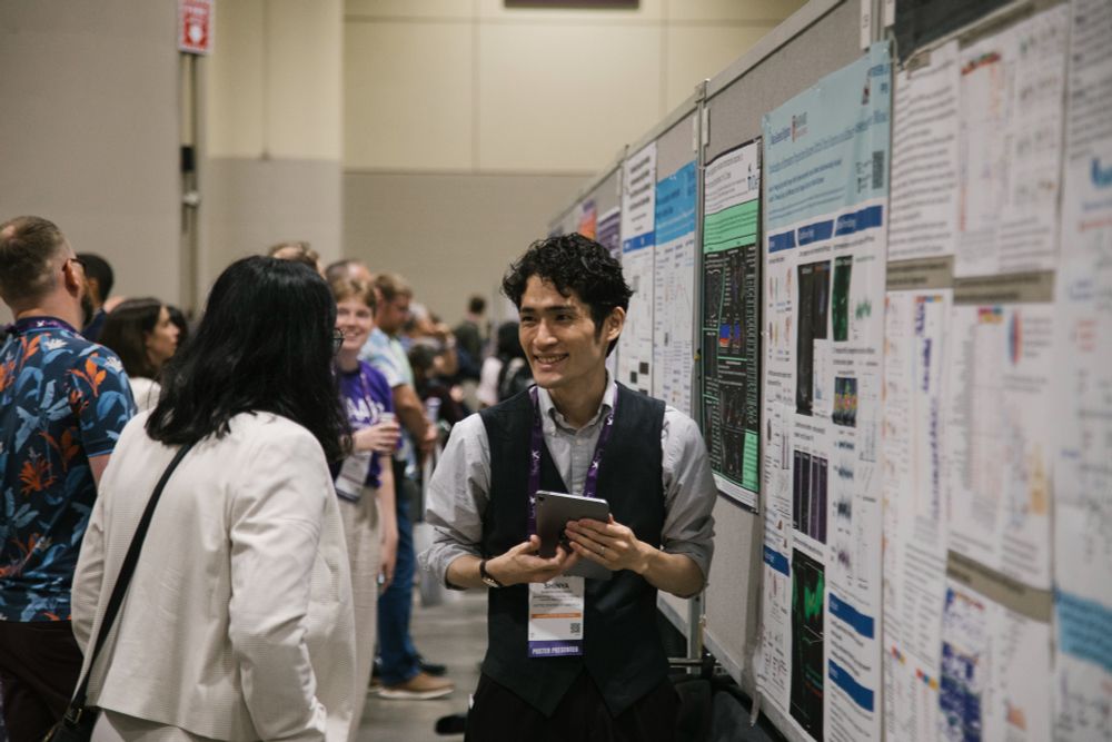 A poster presenter at AAIC25 goes over their poster with an interested attendee.