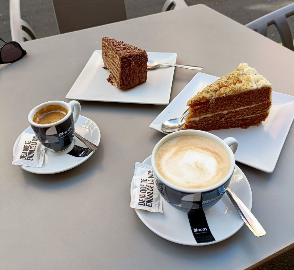 Dos trozos de tarta y dos tazas de café sobre una mesa. 