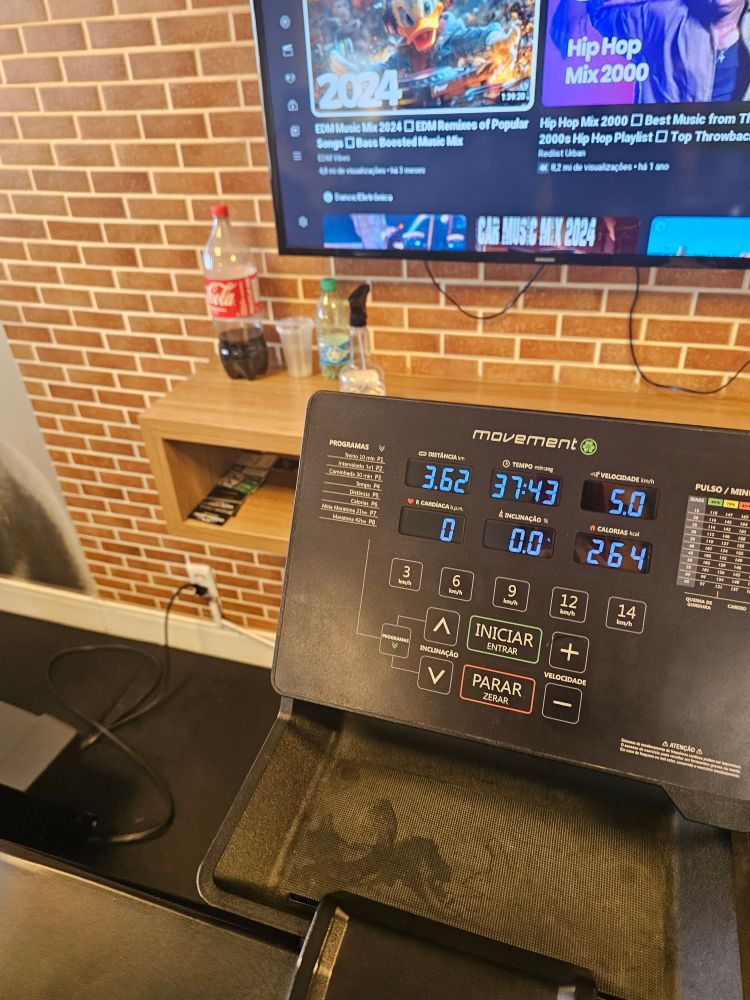 Uma coca cola 2 litros com 1/3 da sua capacidade preenchida aparece numa prateleira dentro da academia.