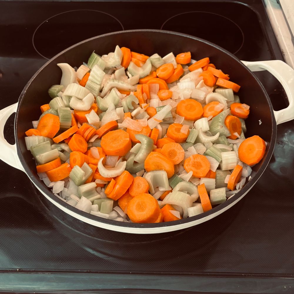 Onions, carrots, and celery sautéed in a pan. 