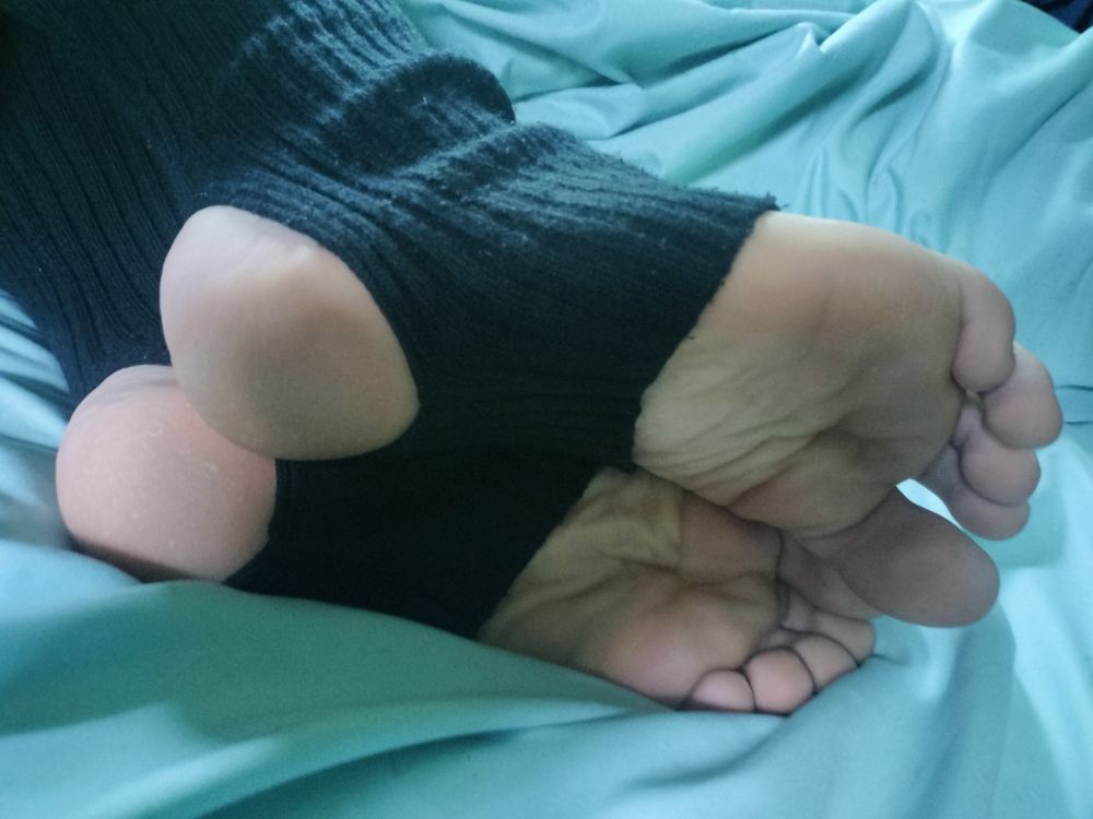 Feet laid by side in bed, wearing stirrups