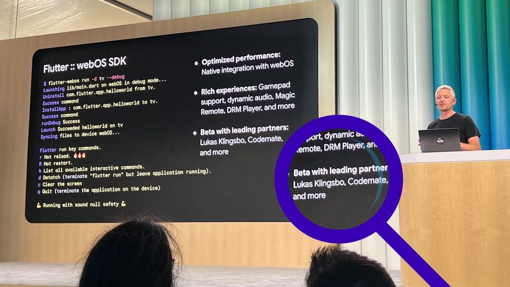 A speaker stands behind a wooden podium with a laptop, presenting at a tech event. On the large screen next to him is a slide about the Flutter webOS SDK, with terminal commands and feature highlights. In the foreground, an audience member's head is visible, and a magnified circle emphasizes a section of the slide mentioning Codemate as one of the partners.